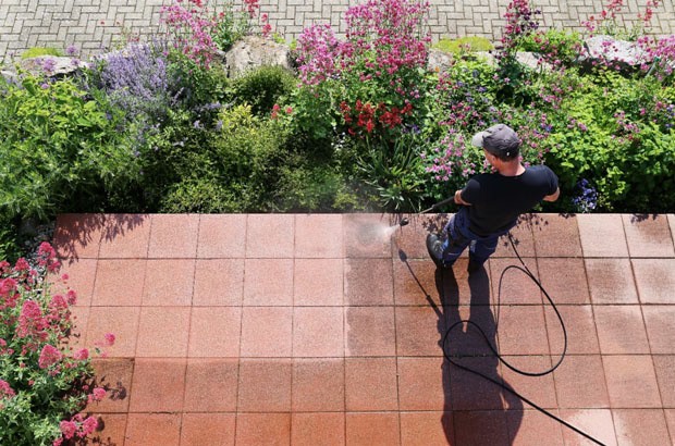 man using high pressure hose to clean outdoor tiles