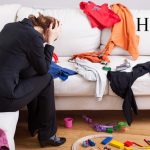 person frustrated at the messy clothes all over the couch and children's toys on the floor