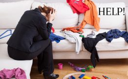 person frustrated at the messy clothes all over the couch and children's toys on the floor