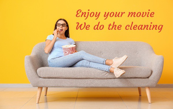 woman eating popcorn watching a movie with her feet up on a couch. Text saying enjoy your movie we do the cleaning