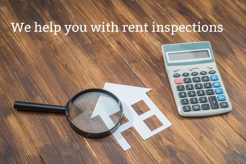 a magnifying glass, calculator and a cutout of a house on a wooden table. Words saying we help you with rent inspections